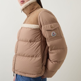 Model wearing Moncler brown quilted down jacket with shearling collar and shoulder panels, arm logo patch, styled with blue jeans