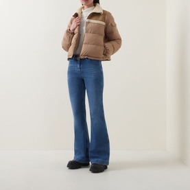 Model wearing Moncler brown wool puffer jacket with contrast panel, styled with blue flare jeans and black shoes