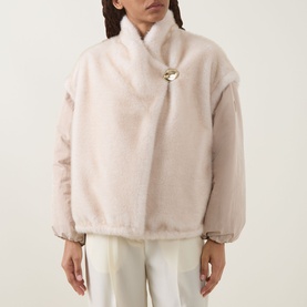 Model wearing Moncler beige faux fur jacket with gold brooch closure, styled with white trousers