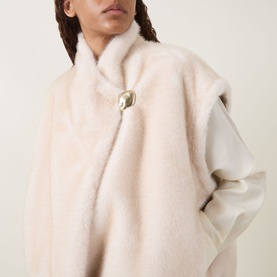 Model wearing Moncler beige faux fur jacket with gold-tone clasp fastening and contrast cream padded sleeves, close-up detail shot