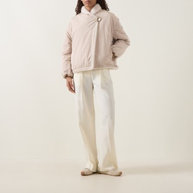 Model wearing Moncler beige padded jacket with asymmetric button fastening, styled with cream wide-leg trousers and flat shoes.