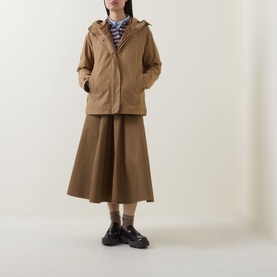 Model wearing Moncler brown cotton hooded jacket, styled with matching midi skirt, striped shirt and black chunky loafers