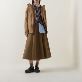 Model wearing Moncler brown cotton hooded jacket, styled with a brown midi skirt, striped top and black loafers