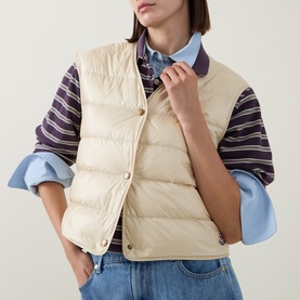 Model wearing Moncler blue quilted down gilet, styled with striped shirt and blue denim jeans