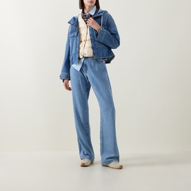 Model wearing Moncler blue padded jacket with wide-leg light-wash jeans, white gilet, and patterned scarf