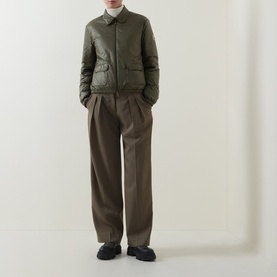 Model wearing Moncler olive quilted down jacket with patch pockets, styled with taupe wide-leg trousers and black loafers