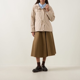 Model wearing Moncler beige jacket with drawstring waist and hood, styled with olive midi skirt and black loafers