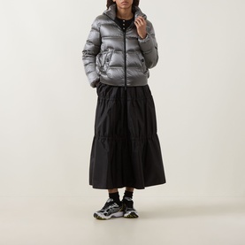 Model wearing Moncler dark grey cropped puffer jacket, styled with black midi skirt and chunky trainers.