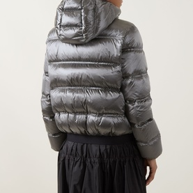 Model wearing Moncler dark grey hooded puffer jacket, back view, styled with black midi skirt. Glossy quilted finish, cropped length.