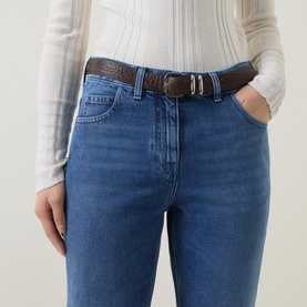 Model wearing Moncler medium blue slim-fit jeans, styled with a cream knit top and brown croc-embossed leather belt.