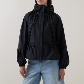 Model wearing Moncler black polyamide parka with hood, logo-trim zip placket, peplum hem, and blouson sleeves, styled with light blue jeans.