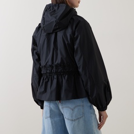 Model wearing Moncler black polyamide parka, rear view showing hooded design, elasticated waist, and balloon sleeves, styled with light blue jeans.
