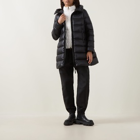 Model wearing Moncler black quilted down parka with hood, styled with white top, black trousers and chunky boots