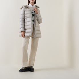 Model wearing Moncler cream quilted down parka with fur-trimmed hood, styled with striped top, cream trousers and black chunky shoes.
