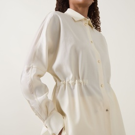 Model wearing Moncler cream shirt with cinched waist, gold buttons, long sleeves and classic collar, cropped three-quarter view