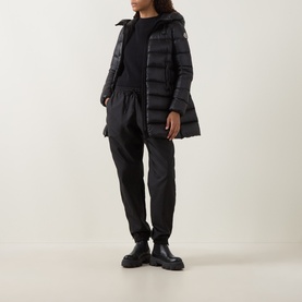 Model wearing Moncler black quilted down parka with hood, styled with black joggers and chunky black boots
