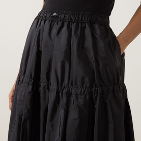 Model wearing Moncler black tiered midi skirt in lightweight polyamide, with elasticated waist and gathered ruched detailing throughout.
