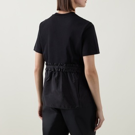 Model wearing Moncler black cotton T-shirt, shown from behind, featuring elasticated ruched waist detail and short sleeves.