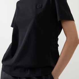 Model wearing Moncler black cotton T-shirt with tonal logo badge and side buckle strap detail, cropped view.
