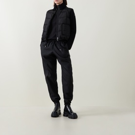 Model wearing Moncler black cotton T-shirt, styled with black padded gilet, black jogger trousers and chunky black boots.