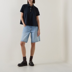 Model wearing Moncler navy cotton polo top, styled with light blue denim shorts and chunky black boots.