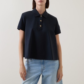 Model wearing Moncler navy cotton polo top with gold-tone buttons and short sleeves, styled with light blue jeans
