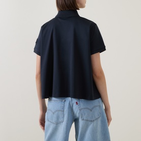 Model wearing Moncler navy cotton polo top, back view, styled with light blue wide-leg Levi's jeans.