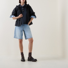 Model wearing Moncler navy cotton top with ruched sleeves, styled with light-wash denim shorts and black chunky boots.
