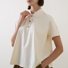 Model wearing Moncler cream cotton polo top with short sleeves and gold-tone buttons, styled with khaki trousers