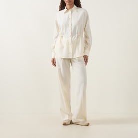 Model wearing Moncler cream wool trousers with wide-leg silhouette, styled with matching cream button-through shirt and beige flats.