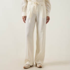 Model wearing Moncler cream wool wide-leg trousers with elasticated waist, styled with a white blouse and beige loafers