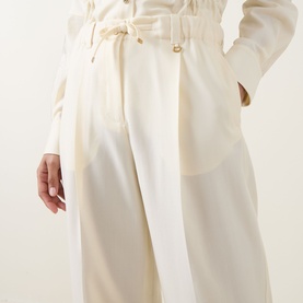 Model wearing Moncler cream wool trousers with elasticated drawstring waist and gold-tone button detail, wide-leg silhouette