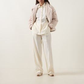 Model wearing Moncler cream wool wide-leg trousers, styled with a white shirt and dusty pink quilted jacket.