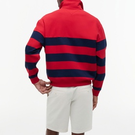 Model wearing Tommy Hilfiger medium red and navy bold stripe half-zip sweatshirt, styled with white shorts, back view.