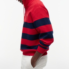 Model wearing Tommy Hilfiger medium red and navy bold stripe hoodie sweatshirt, styled with white trousers.