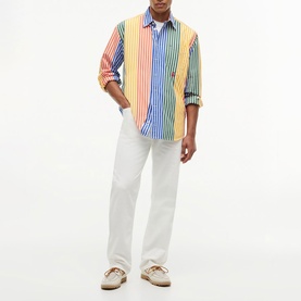 Model wearing Tommy Hilfiger orange multicolour striped long-sleeve shirt with white straight-leg trousers and beige loafers.