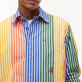 Model wearing Tommy Hilfiger multicolour stripe shirt in orange-based rainbow vertical stripes with chest pocket and embroidered logo