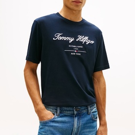 Model wearing Tommy Hilfiger navy script logo crew neck T-shirt, styled with light wash denim jeans.