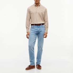 Model wearing Tommy Hilfiger Rio Blue slim-fit jeans with a beige check shirt, brown belt, and boat shoes.