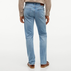 Model wearing Tommy Hilfiger jeans in Rio Blue, straight leg fit, shown from behind, styled with a brown checked shirt and loafers.