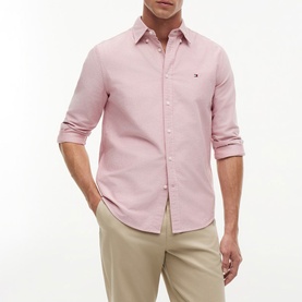 Model wearing Tommy Hilfiger medium red long-sleeve Oxford shirt with button-down collar, styled with beige chinos.