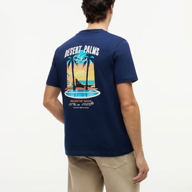 Model wearing Tommy Hilfiger Carbon Navy t-shirt, back view showing Desert Palms graphic print, styled with beige chinos