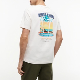 Model wearing Tommy Hilfiger Ivory Petal T-shirt with Desert Palms graphic print on back, styled with khaki shorts.