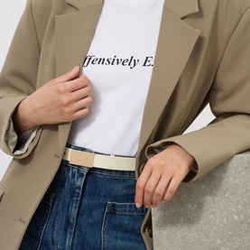 Model wearing Victoria Beckham Portofino Mirror Leather Belt in ivory with gold-tone hardware, styled with blue jeans and beige blazer.
