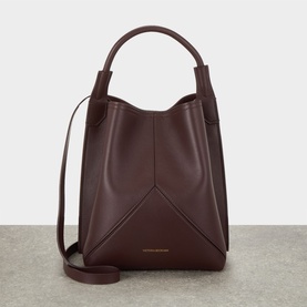 Victoria Beckham Victoria Bucket Bag in dark burgundy leather, gold-tone logo, top handle and detachable crossbody strap