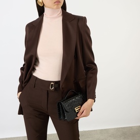 Model carrying Victoria Beckham Dorian Small Crossbody Bag in black croc-embossed patent leather with gold-tone hardware, styled with brown suit