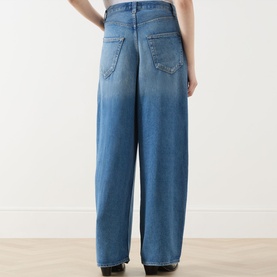 Model wearing AgoldE Rounded Baggy Wide-Leg Jeans in Expression mid wash, showing rear five-pocket detail and wide-leg silhouette