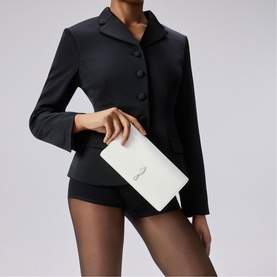 Model carrying Christian Louboutin white clutch bag with embellishment detail, styled with black blazer and shorts