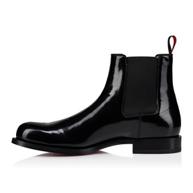 Christian Louboutin black patent leather Chelsea boot, elastic side panel, block heel, and signature red sole visible on men's style.