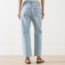 Model wearing Citizens of Humanity Winslow Boyfriend Jeans in Horizon light wash, straight leg, tobacco stitching, rear logo patch, with brown flat